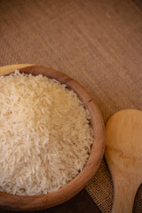Uncooked Jasmine rice in wooden bowl on the table. Jasmine rice has a subtle floral aroma and a soft, sticky texture when cooked. 