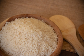 Uncooked Jasmine rice in wooden bowl on the table. Jasmine rice has a subtle floral aroma and a soft, sticky texture when cooked. 