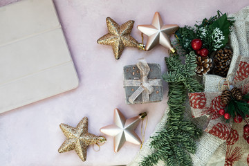 Golden stars, gift box, cover of tablet, christmas tree branch and decorations on light pink textured background. Christmas, new year, winter concept. Flat lay, top view, copy space