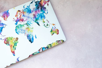 Laptop with map of world on light pink textured background. Modern present concept, travel, discover