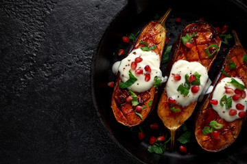 Grilled eggplants with yogurt sauce, pomegranate seeds, parsley and green onion in cast iron vintage pan.