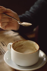 The girl stirs sugar in a cup of coffee. Close-up, lifestyle. Tinted photo.
