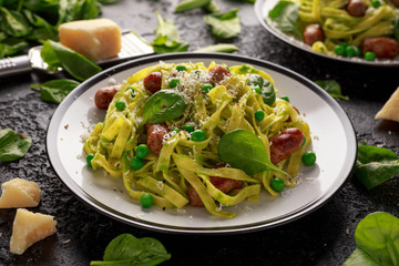 Homemade Pasta with green peas, spinach pesto and sausages. parmesan cheese. healthy food.