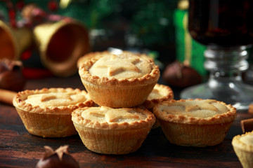 British Christmas mince pies with decoration, gifts, green tree branch on wooden rustic table