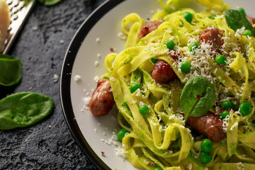 Homemade Pasta with green peas, spinach pesto and sausages. parmesan cheese. healthy food. close up