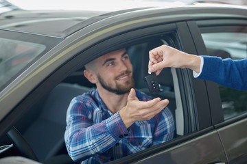 Brunette guy getting key from manager after buying vehicle. 
