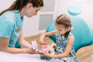 Obraz na płótnie Canvas pediatric dentist teaches little girl to brush teeth