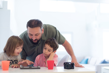 single father at home with two kids playing games on tablet