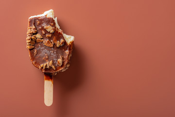 top view chocolate outer ice cream with peanuts on a brown background with some bites