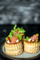 French cuisine, crunchy patties with lettuce and smoked salmon on a dark, rustic background
