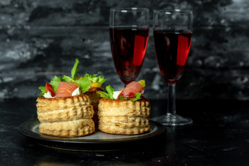French cuisine, crunchy patties with lettuce and smoked salmon on a dark, rustic background, next to a glass of red wine