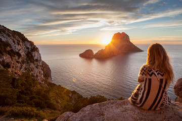 Woman back to the front watching a beautiful sunset at the beach. The beach is called Es Vedra - obrazy, fototapety, plakaty