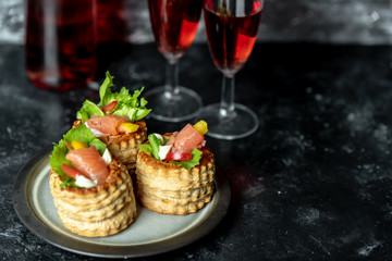 French cuisine, crunchy patties with lettuce and smoked salmon on a dark, rustic background, next to a glass of red wine