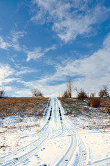 Road in the snow against the bright blue sky.