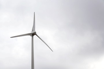 Fototapeta premium White wind turbine power station, foggy day, copy space on cloudy sky, sustainable renewable electricity concept