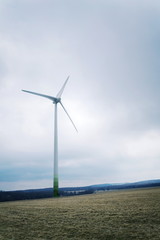 White wind turbine power station, foggy day, copy space on cloudy sky, sustainable renewable electricity concept