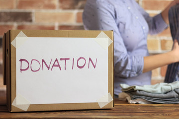 Volunteer is puting clothes to cardboard box for donation