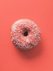 Color of year 2019 Living Coral concept. Donut with living coral glaze on coral paper background. Top view or flat lay. Copy space for text.