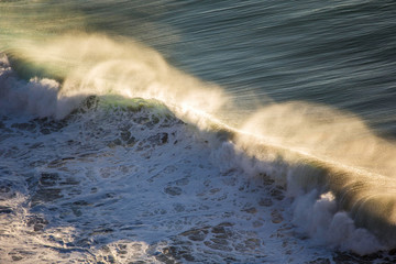 Crashing wave at sunset with foam on left and stripes on the right © Bruno