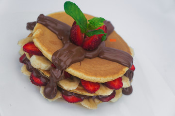 Pancake with fresh strawberry and banana topped on chocolate sauce
