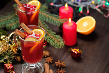 Mulled wine on a wooden background with candles, pine branches and Christmas lights. Selective focus