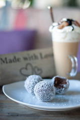 Chocolate balls on white plate and cafe latte with caramel chocolate on top