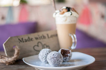 Chocolate balls on white plate and cafe latte with caramel chocolate on top