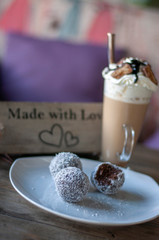 Chocolate balls on white plate and cafe latte with caramel chocolate on top
