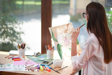 Female artist looking at picture of flower.