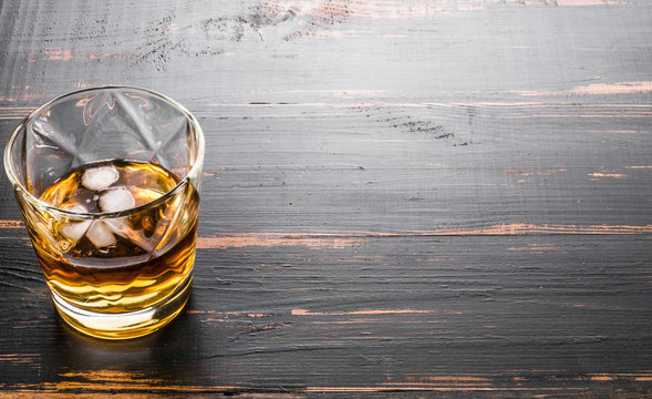 glass of whiskey on dark wooden tabletop