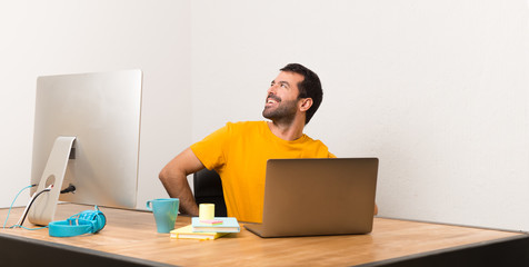 Man working with laptot in a office posing with arms at hip and laughing