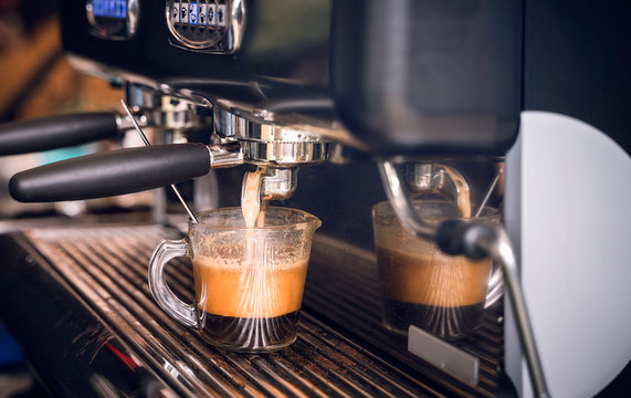 coffee machine preparing fresh coffee and pouring into glass cup