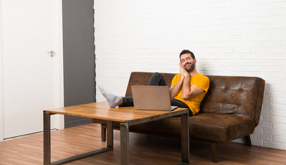 Man with his laptop in a room making sleep gesture in dorable expression