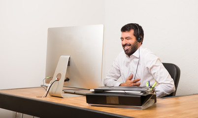 Telemarketer man in a office smiling a lot while putting hands on chest