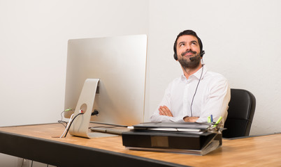 Telemarketer man in a office looking up while smiling