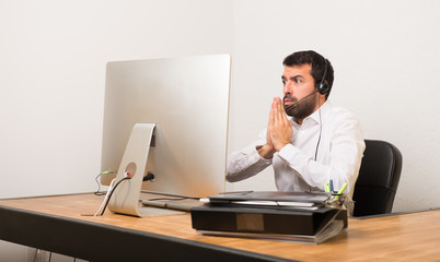 Telemarketer man in a office keeps palm together. Person asks for something