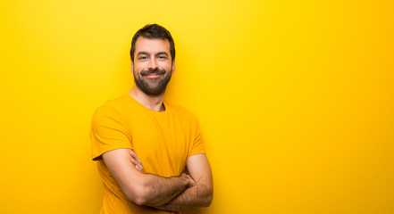 Man on isolated vibrant yellow color keeping the arms crossed in lateral position while smiling