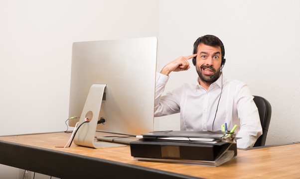 Telemarketer Man In A Office Making The Gesture Of Madness Putting Finger On The Head