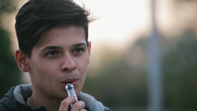 portraite of vaping young boy outdoors in the evening