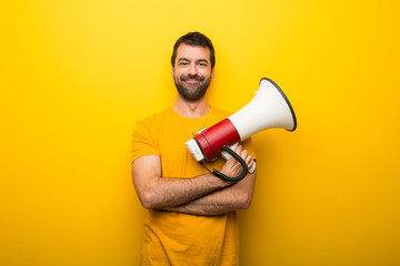Man on isolated vibrant yellow color holding a megaphone