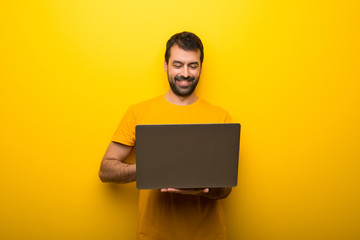 Man on isolated vibrant yellow color with laptop