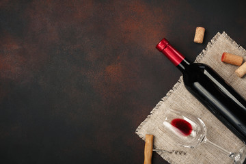 Bottle of wine, glasses, corkscrew and corks, on rusty background top view