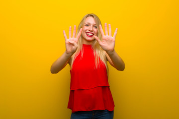 Young girl with red dress over yellow wall counting nine with fingers