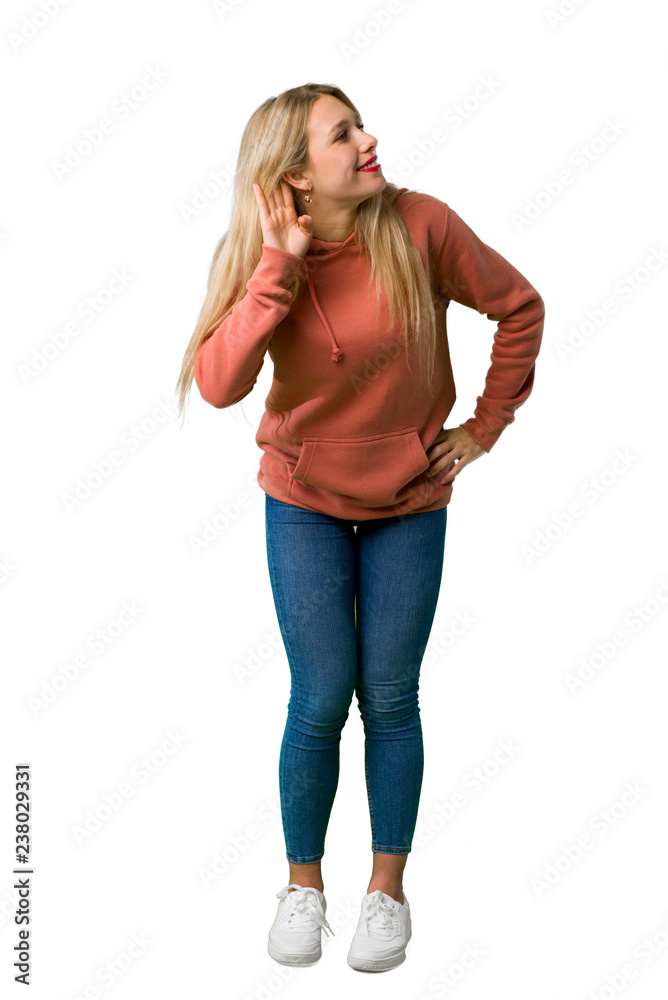 Wall mural A full-length shot of a Young girl listening to something by putting hand on the ear on isolated white background