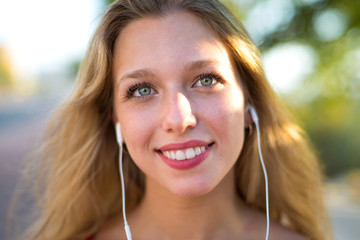 Young blonde girl listening to music with headphones