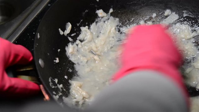 mans hands washing a pan with sticky food stuff in the kitchen