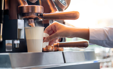 Barista making a take away coffee cup with coffee machine.