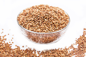 Buckwheat grain in glass bowl on white background. Isolated on white