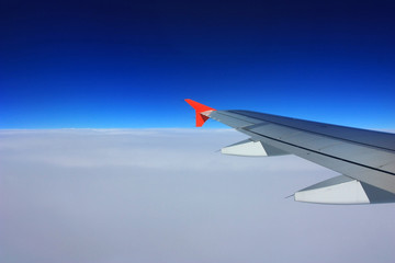 Obraz premium Airplane wing in the blue sky