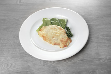 chicken with cheese on white plate on wooden background